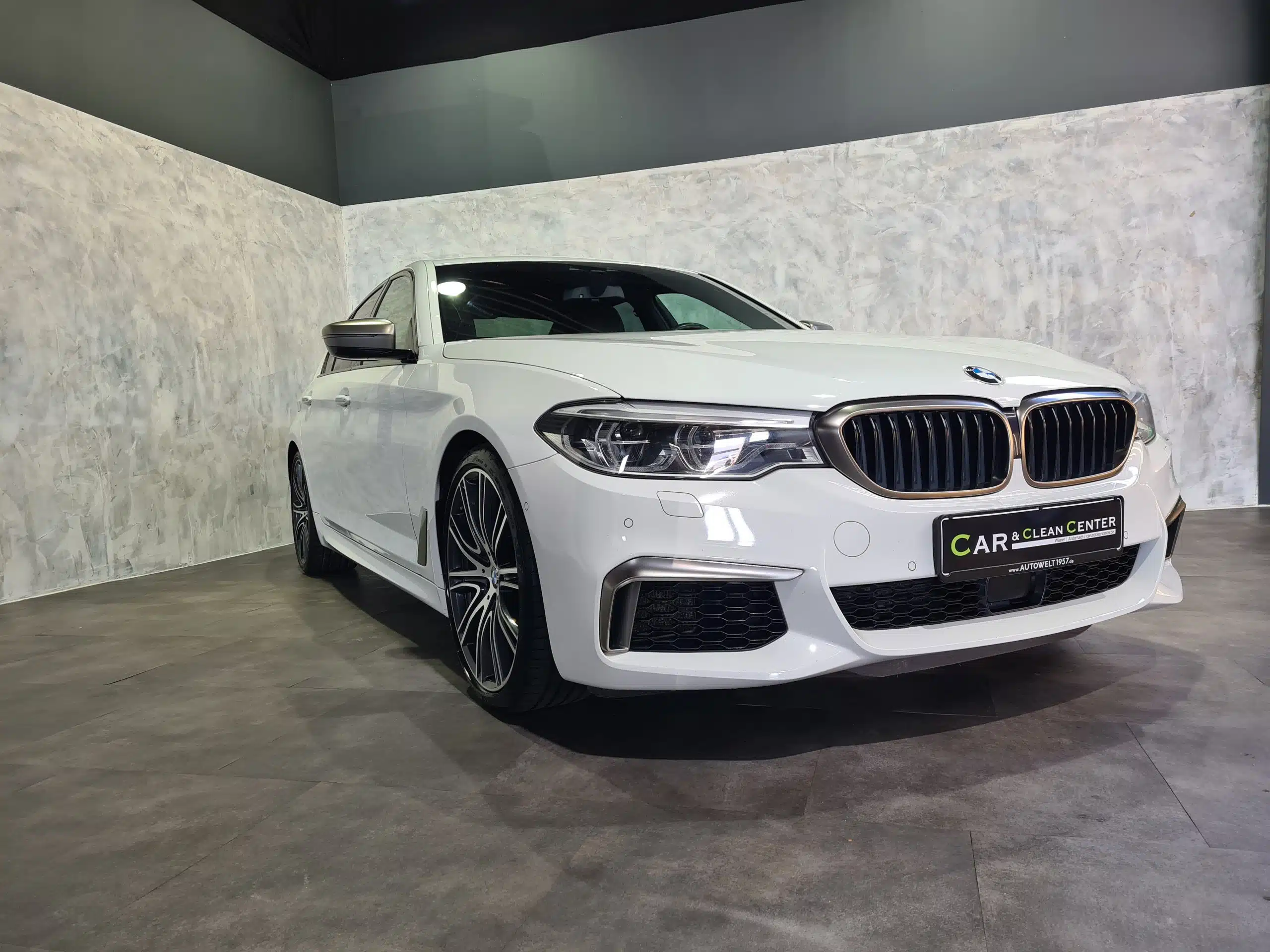 Weißer BMW im Showroom des Car & Clean Centers nach professioneller Fahrzeugaufbereitung.