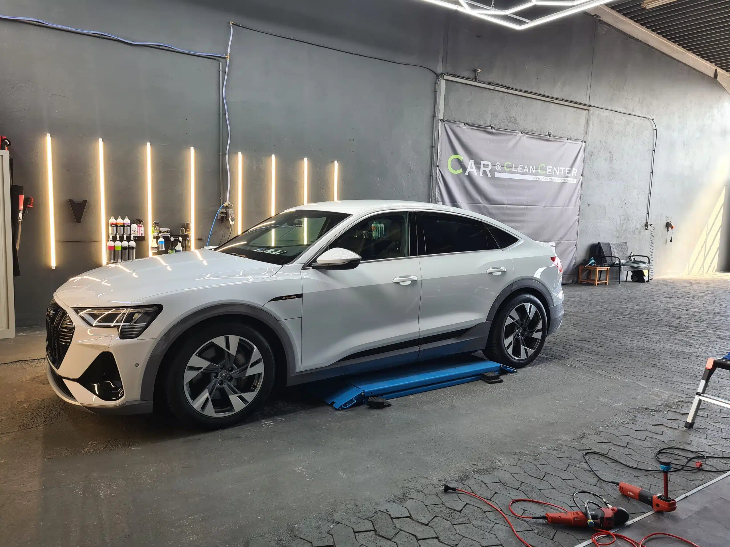 Weißer Audi e-tron in der Aufbereitungshalle des Car & Clean Centers.