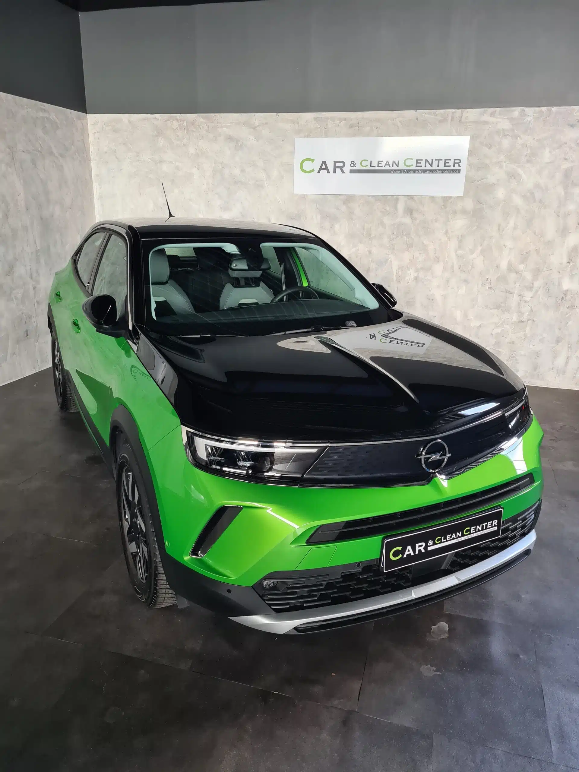 Grün-schwarzer Opel SUV nach professioneller Aufbereitung im Präsentationsbereich des Car & Clean Centers.