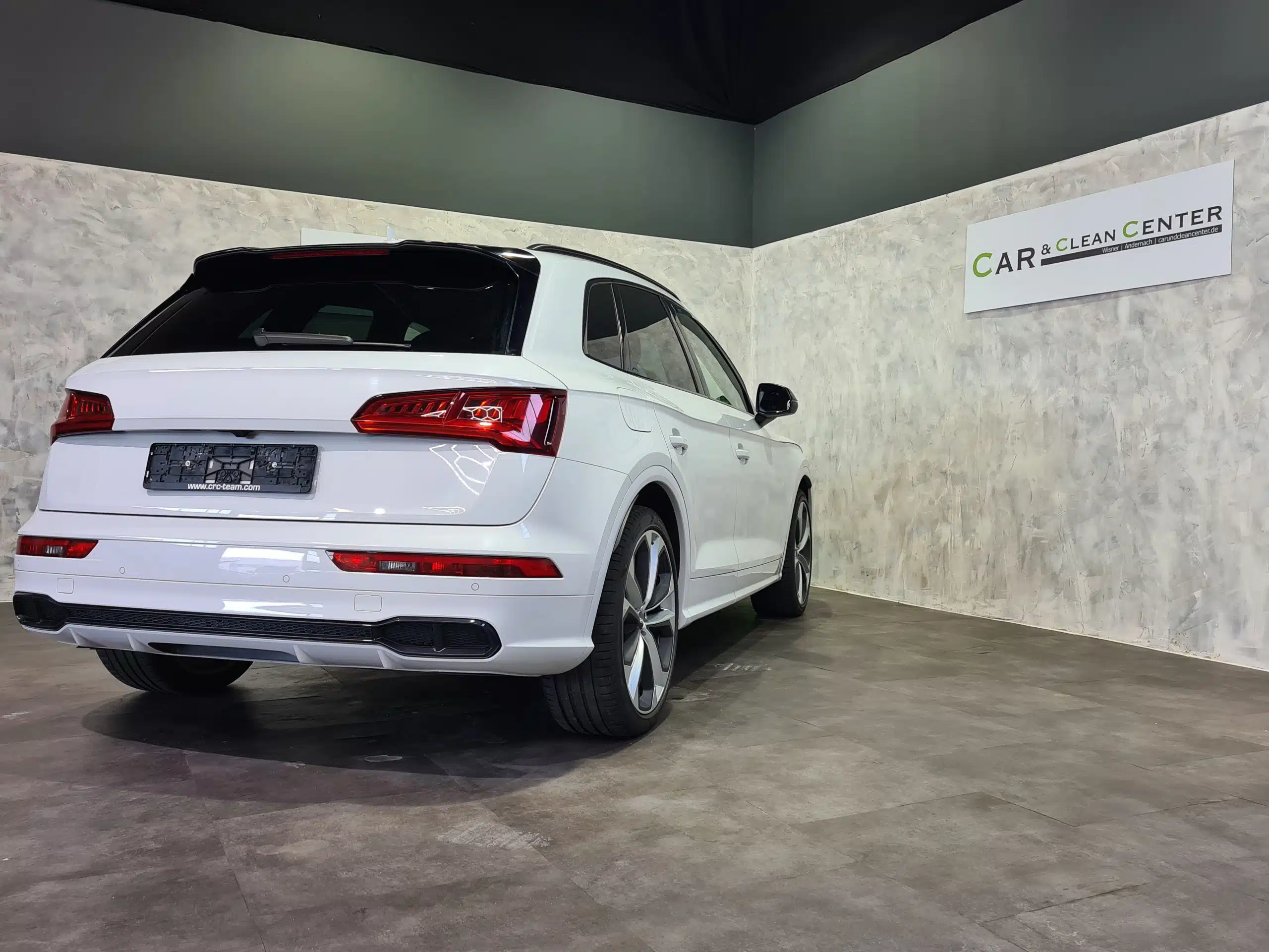 Weißer Audi Q5 in Fotobox-Umgebung, Rückansicht mit dekorativem Wandlogo.