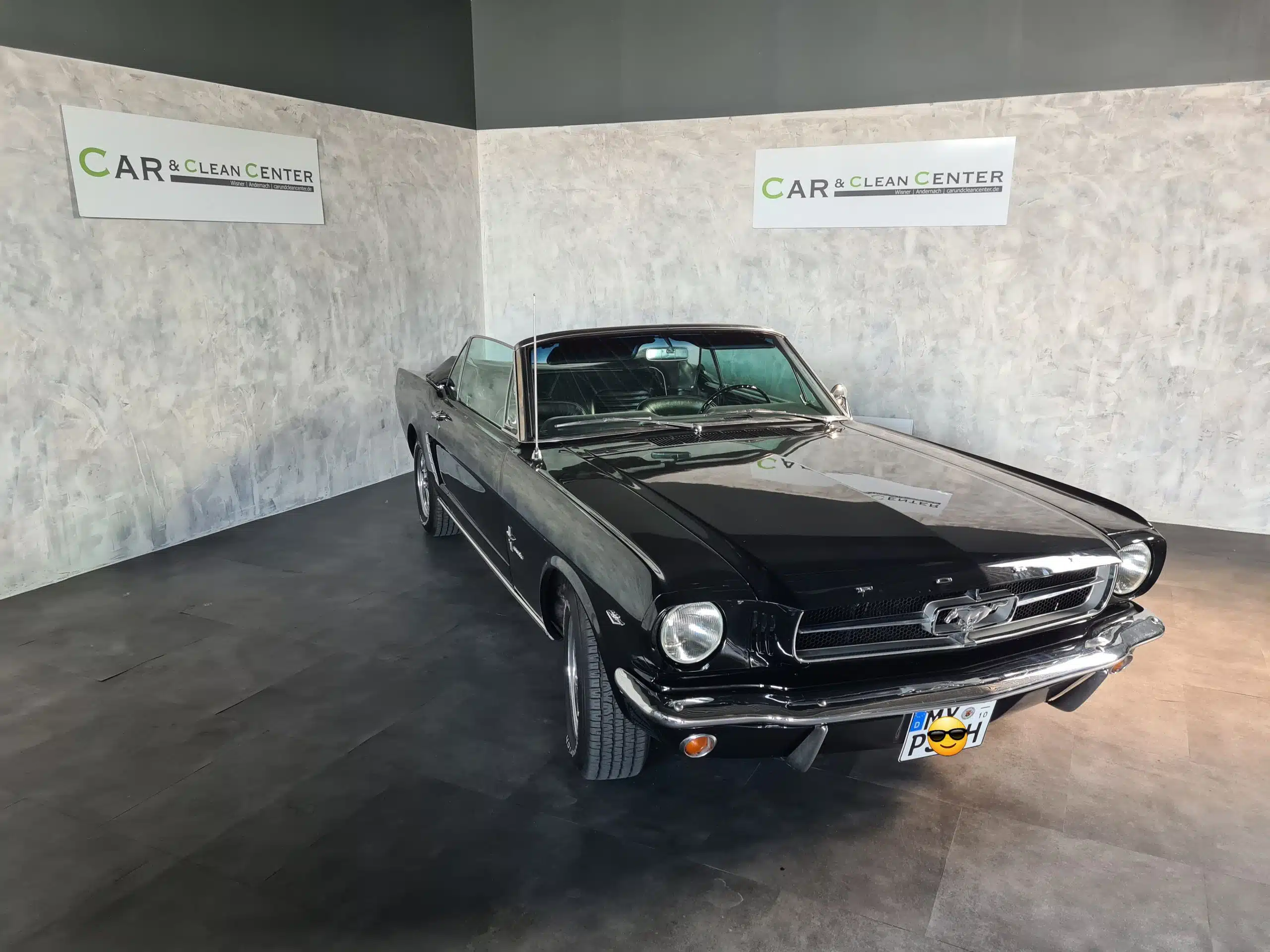Schwarzer Ford Mustang Oldtimer im Showroom des Car & Clean Centers nach professioneller Fahrzeugaufbereitung.