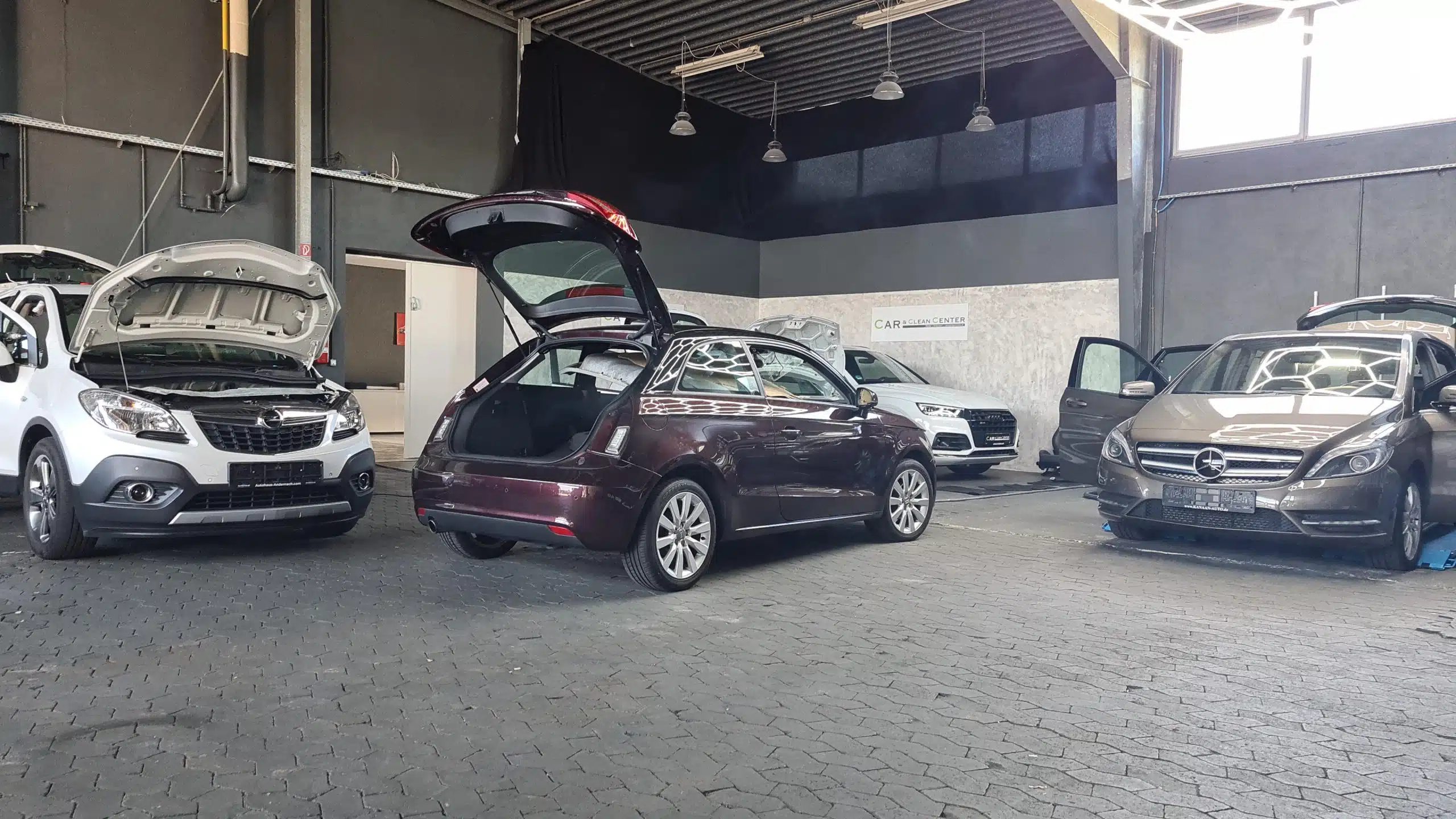 Grauer Fiat 500 Abarth 595 in einer Fotobox mit grauem Betonboden und hellem Struktur-Hintergrund, seitlich fotografiert.
