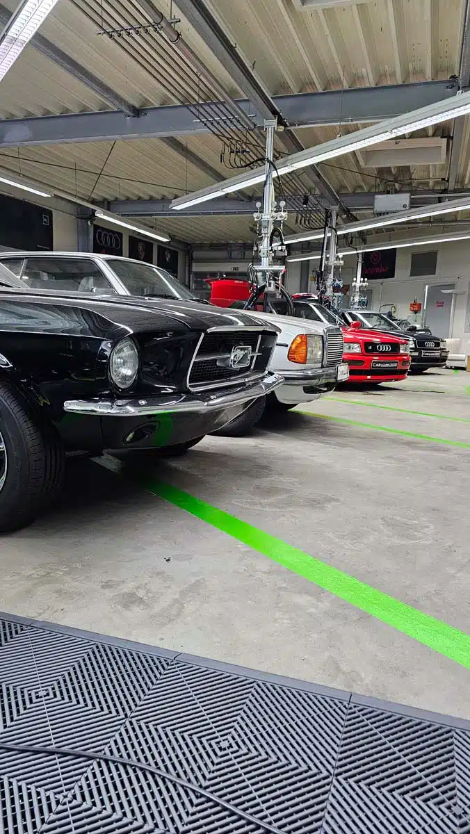 Reihe klassischer und moderner Fahrzeuge im Detailing-Bereich des Car & Clean Centers, bereit für Aufbereitungsarbeiten.