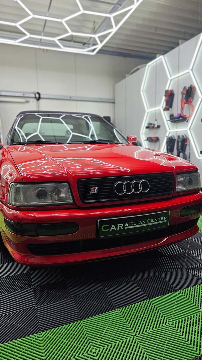 Roter Audi S-Modell-Klassiker im modernen Detailing-Studio des Car & Clean Centers mit hexagonaler LED-Beleuchtung.