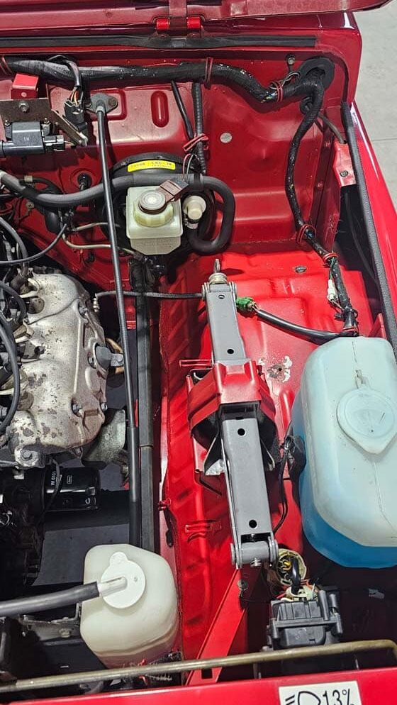 Motorraum eines roten Fahrzeugs nach Reinigung, mit sichtbarer Batterie, Luftfiltereinheit und sauberen Bauteilen.