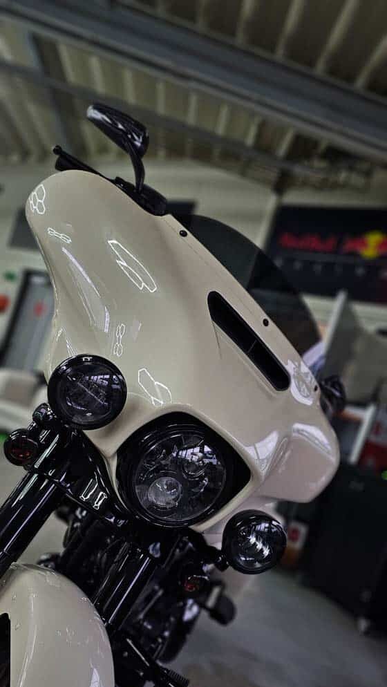 Frontansicht eines cremefarbenen Motorrads nach professioneller Aufbereitung mit glänzender Verkleidung und klaren Lichtreflexionen.