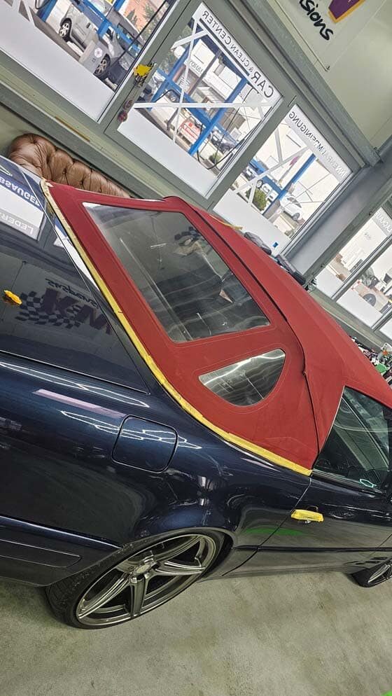 Cabrio mit rotem Verdeck und abgekleidetem Rand zur Vorbereitung einer Fahrzeugaufbereitung im Detailing-Studio.