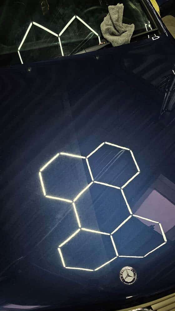Reflektierende hexagonale LED-Lichtmuster auf der frisch polierten Motorhaube eines Mercedes.