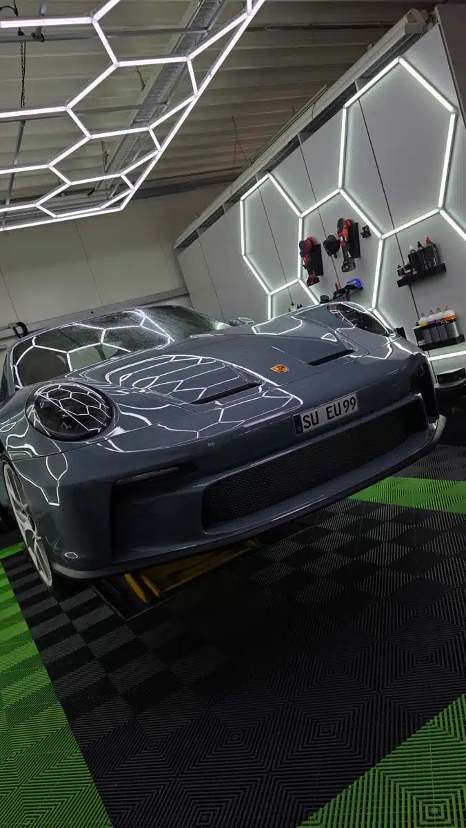 Porsche in professioneller Detailing-Halle mit hexagonaler LED-Beleuchtung und makellos glänzendem Lack.