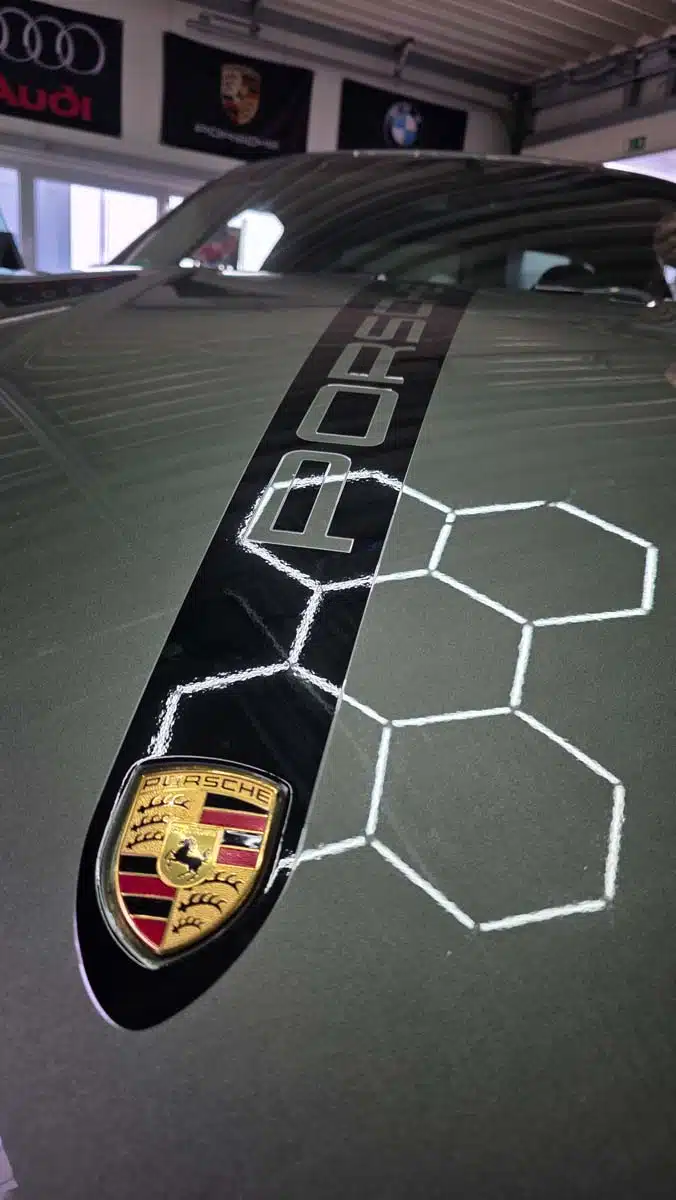 Porsche-Front mit schwarzem Mittelstreifen und reflektierender Wabenstruktur nach professioneller Lackaufbereitung.