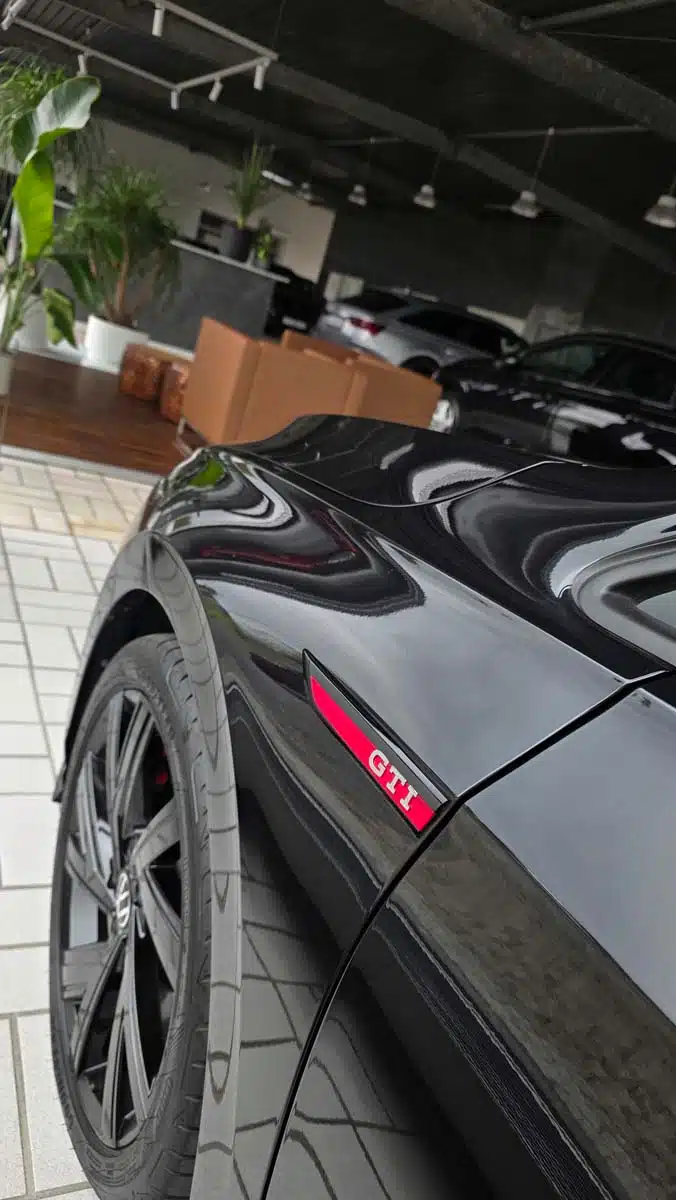 Schwarzer GTI mit hochglänzendem Lackfinish in einer modernen Fahrzeughalle.