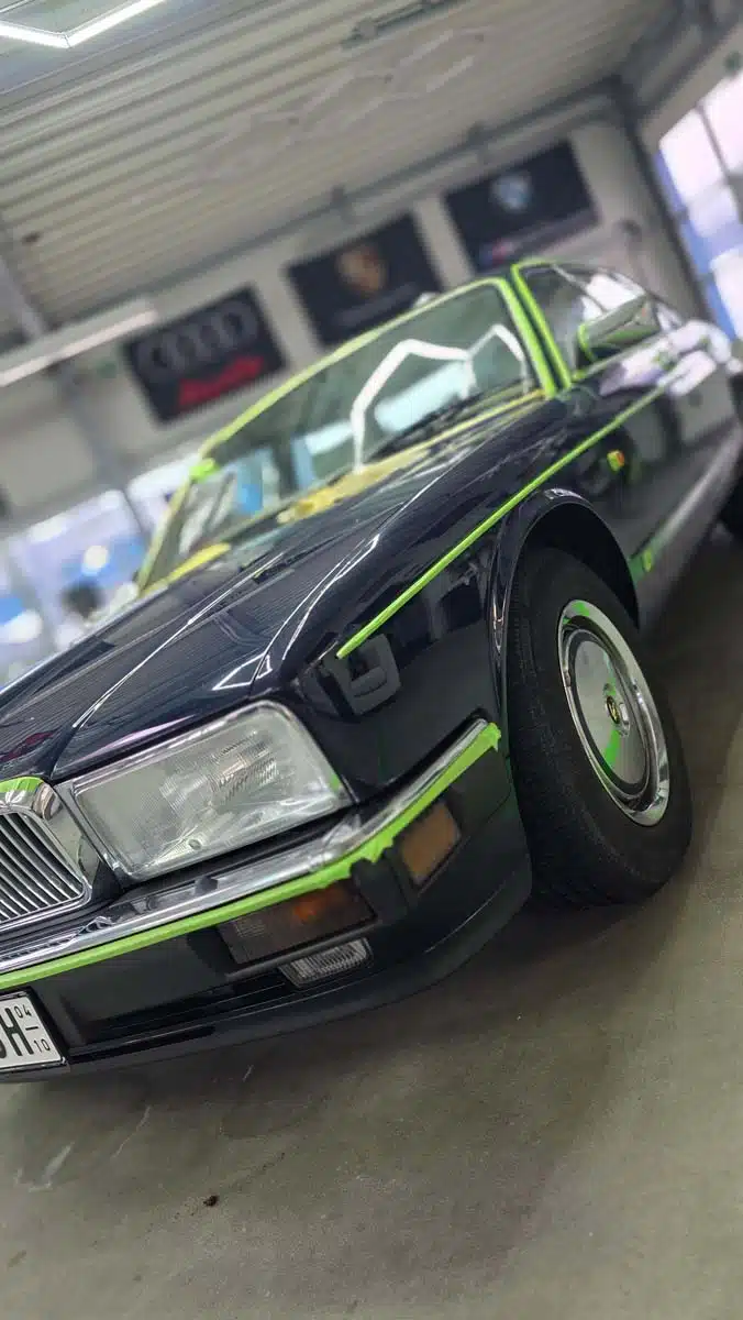 Klassisches Fahrzeug in der Werkstatt von C&C Andernach, mit grünem Abklebeband für die Lackpolitur vorbereitet.