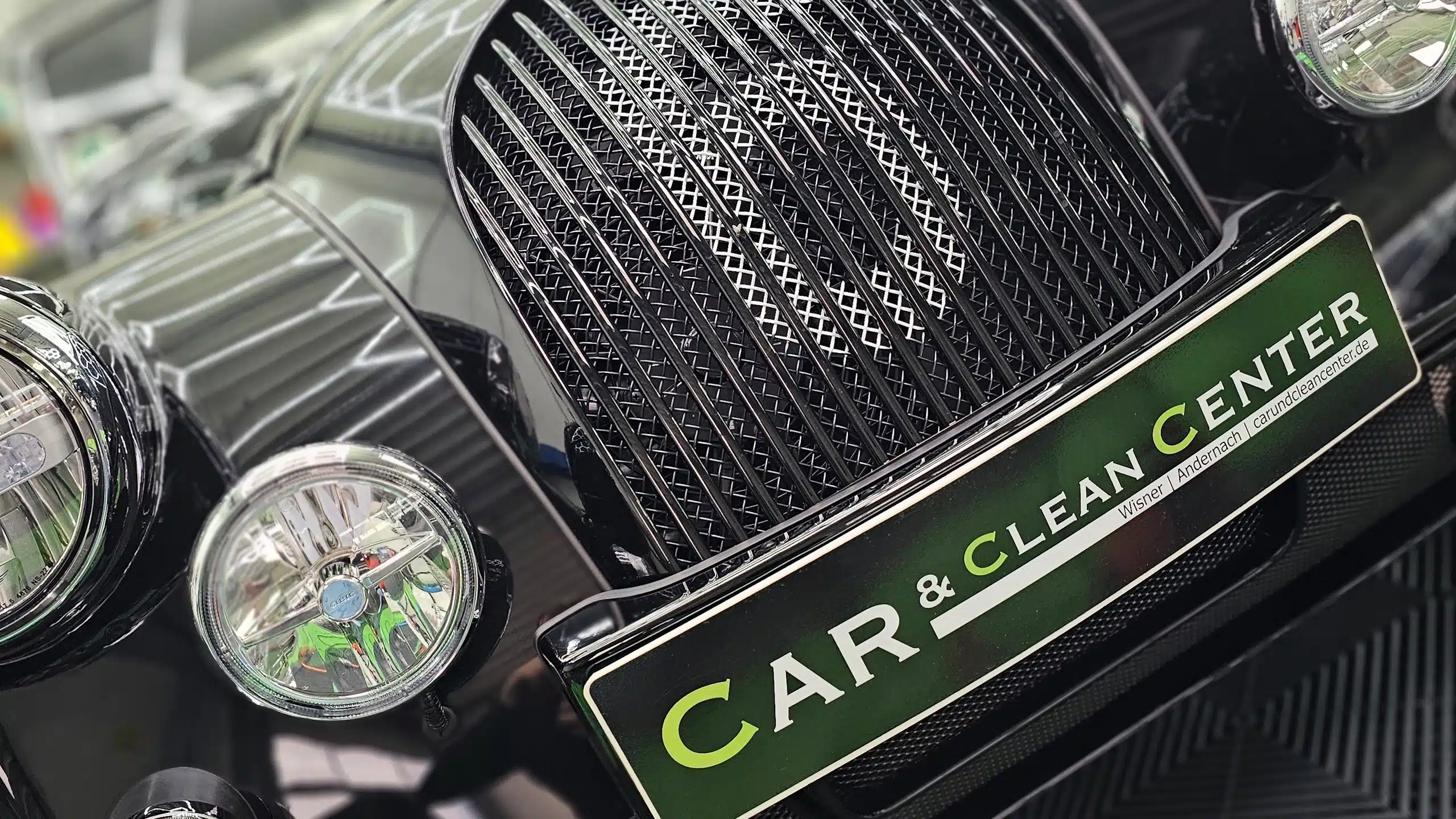 Frontansicht eines klassischen schwarzen Fahrzeugs mit CAR & CLEAN CENTER Kennzeichenplatte im Detailing-Studio.
